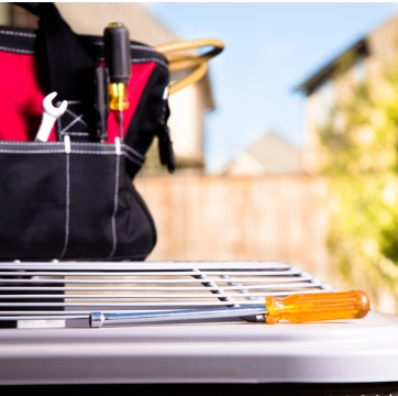 A tool bag sitting on top of an outdoor AC unit in need of repair