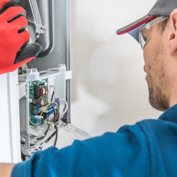 A technician looking a wiring for a furnace during Heating Installation in Bloomington IL