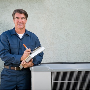 A repairman looks over an air conditioner after someone searched Appliance Repair in McLean County IL