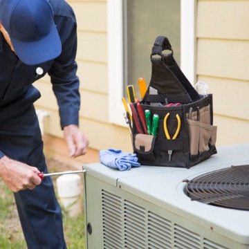 A serviceman is unscrewing a bolt while performing AC Maintenance in Peoria IL