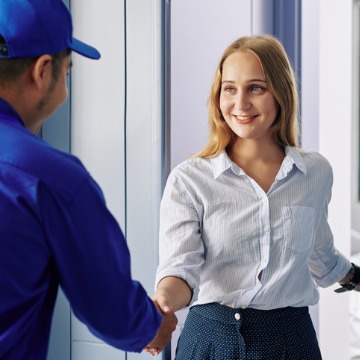 A woman smiles and shakes hands with a repairman after he performs Refrigerator Repair in Pekin IL