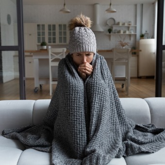 A woman sits wrapped up in a blanket after calling for Heating Service in Bloomington IL