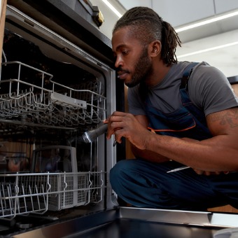 A repairman works on a dishwasher. Chambers Services also offers Furnace Service in Bloomington IL