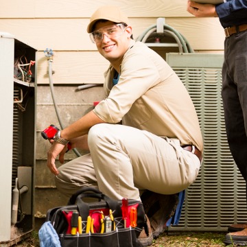 A employee of Chambers Services smiles while fixing an air conditioner after the homeowner calls for a Heating and Cooling Company in Bloomington IL