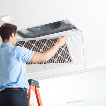 A team member of Chambers Services cleans a filter as part of a routine Duct Cleaning in Normal IL