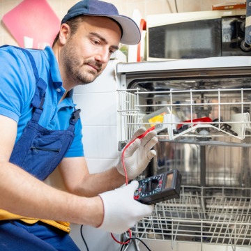 A repairman works on a washing machine, which is just one of the services Chambers Services offers in addition to Heating Repair in Lincoln IL