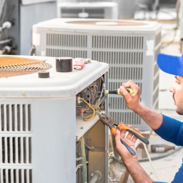 A technician adjusting the electrical wiring of an AC unit during AC repair in Bloomington IL