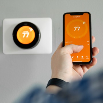 A man controlling a smart thermostat in Central Illinois by using his phone