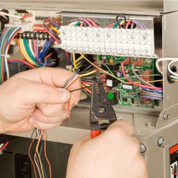 A technician fixing the wiring for a furnace during heating service in Illinois