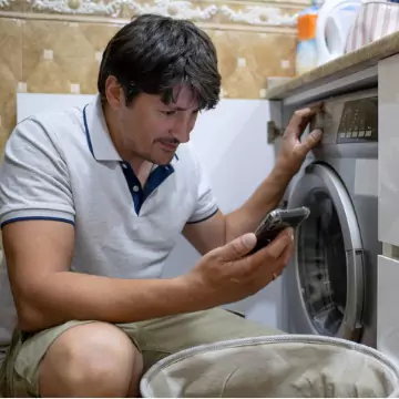 A man looks stressed as he stares at his phone, ready to call for Dryer Repair in Peoria IL