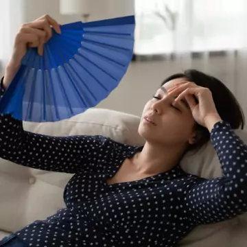 A woman fans herself because her AC is Running But Not Cooling