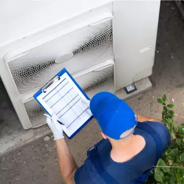 A Chambers Services technician performing an inspection of an outdoor air conditioning unit during AC Maintenance in Bloomington IL