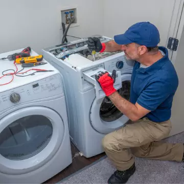 A young appliance tech performing Washing Machine Repair on a broken washer in Central Illinois