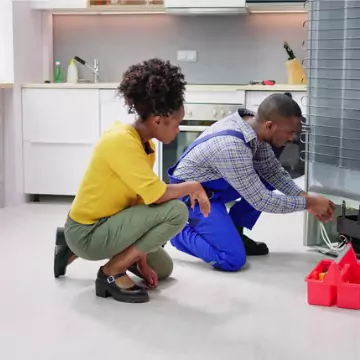 A Chambers Technician looking at a refrigerator with a young woman, performing Refrigerator Repair in Central Illinois