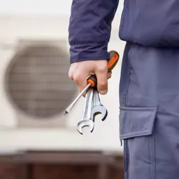 A technician holding tools, ready to provide Heating and Cooling Services in Peoria, Bloomington, Champaign, and across Central Illinois