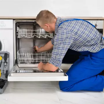 A man getting into a dishwasher to diagnosis the problem as a part of Dishwasher Repair services from Chambers Services