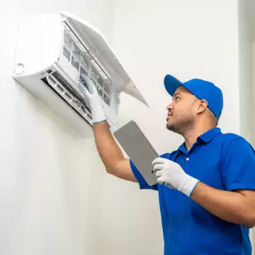 A Chambers Services technician providing reliable HVAC and appliance service in Bloomington-Normal for a AC unit on a wall