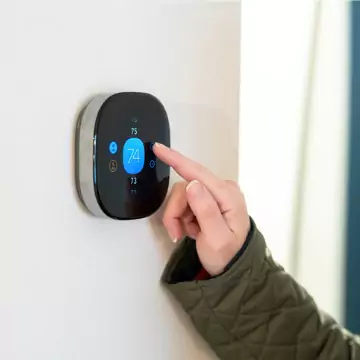 A woman adjusting the temperature in her home using a Smart Thermostat